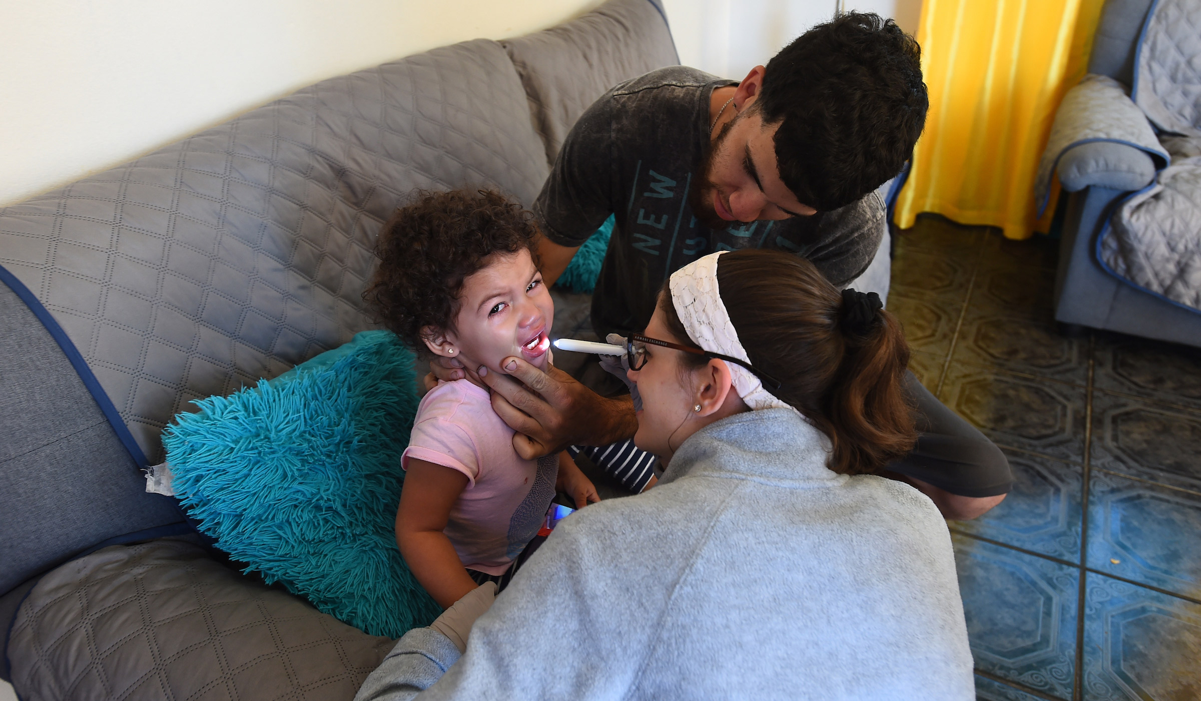 A nursing student inspects a child's throat while going on house visits