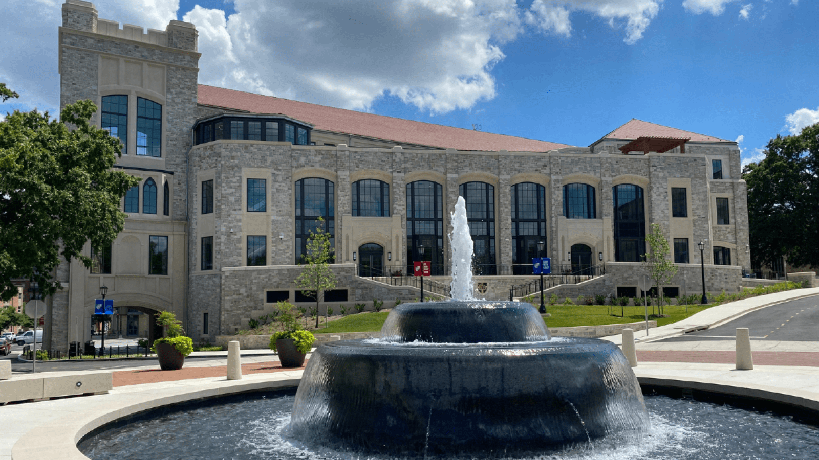 The new Conway School of Nursing building in the summer with the full green trees and a blue sky.