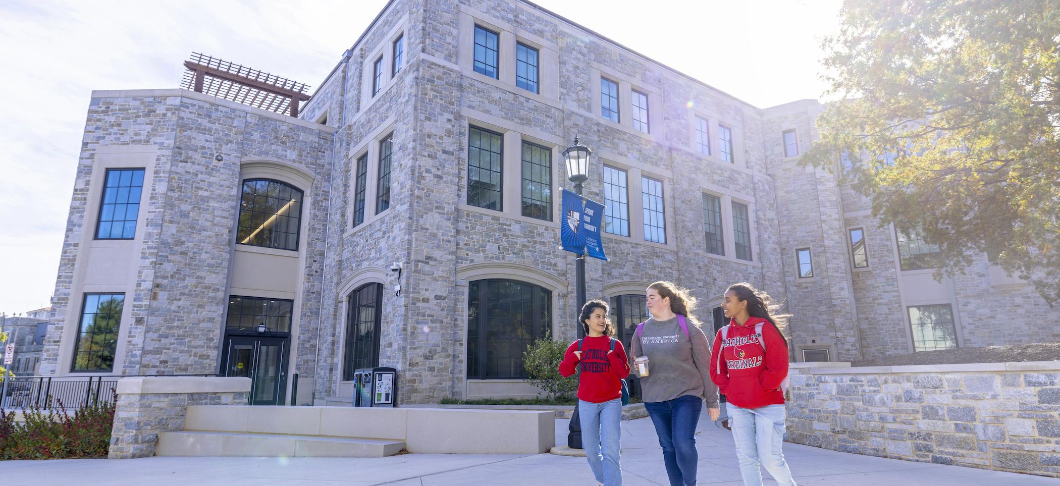 Three female students walking outside of the conway building