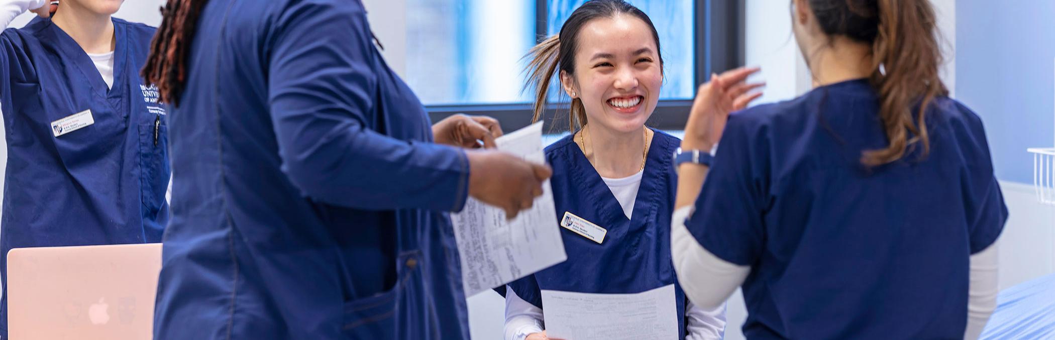 Nursing students reviewing procedures in exam room.