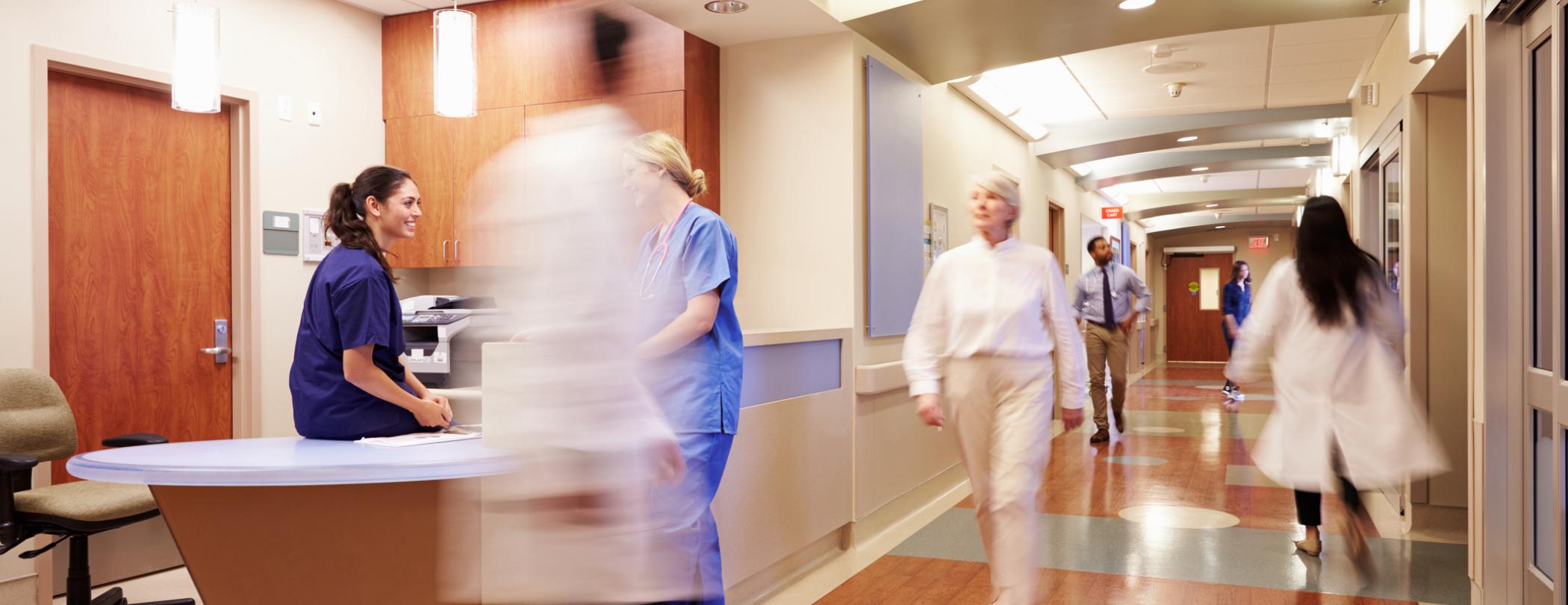 hospital hallway with nurses and doctors swiftly walking by