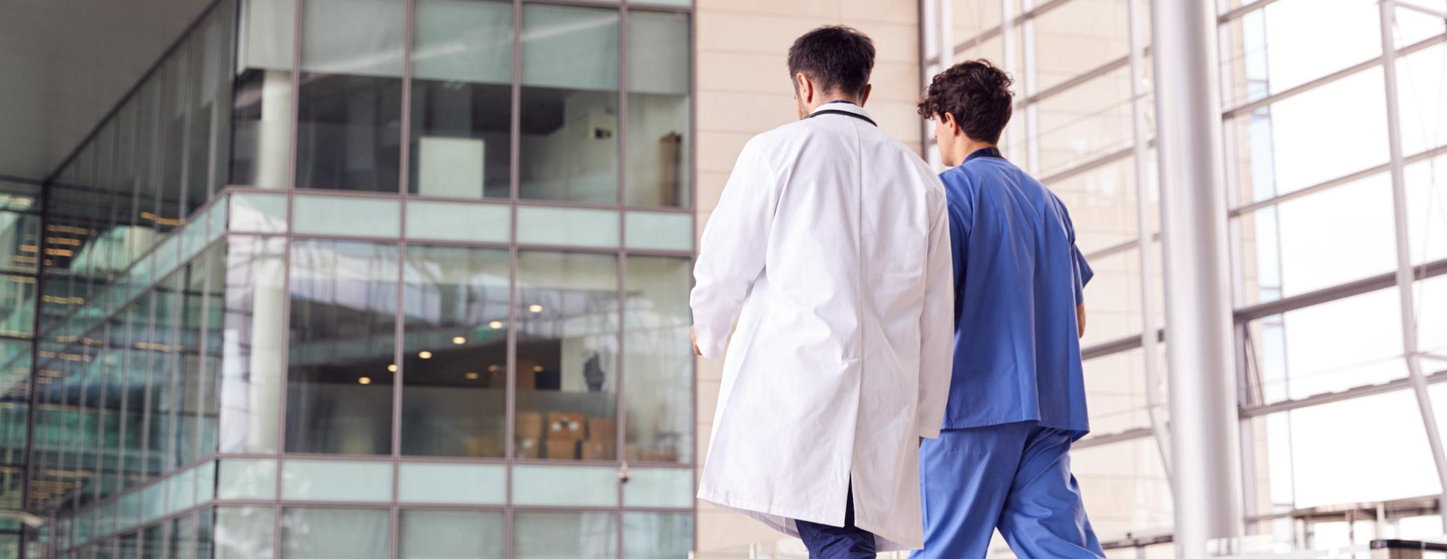 a male nurse and doctor, outside, walking away from the hospital