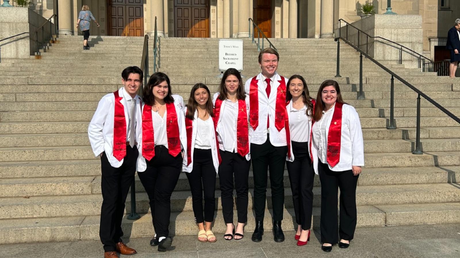 elizabeth and her nursing friends in their white nursing lab coats and red stoles after a nursing ceremony