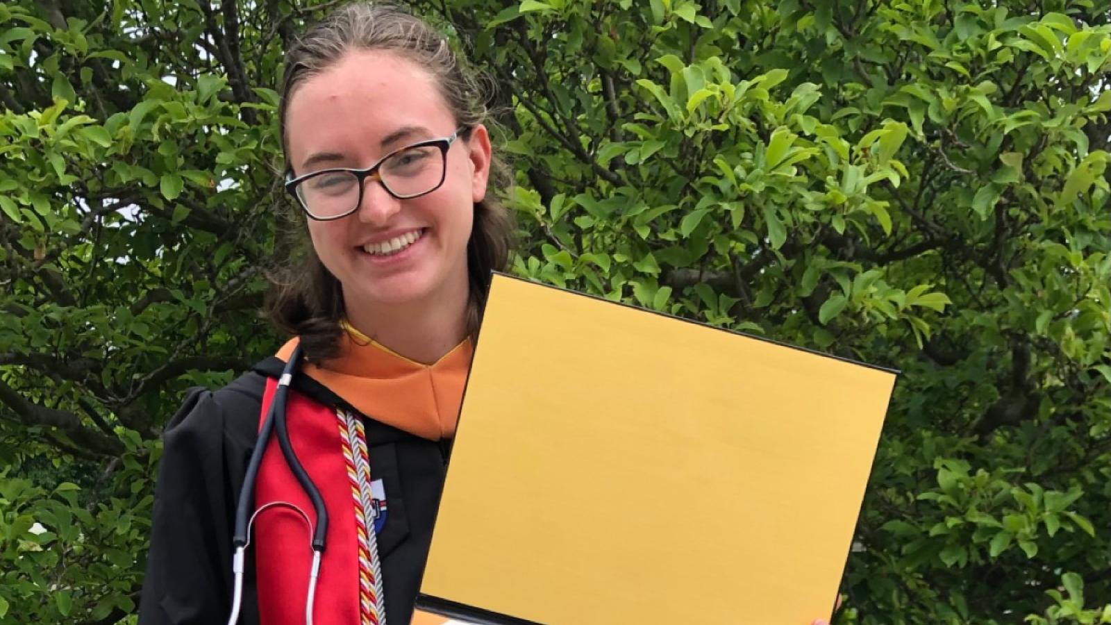 amanda smiles with her diploma at graduation