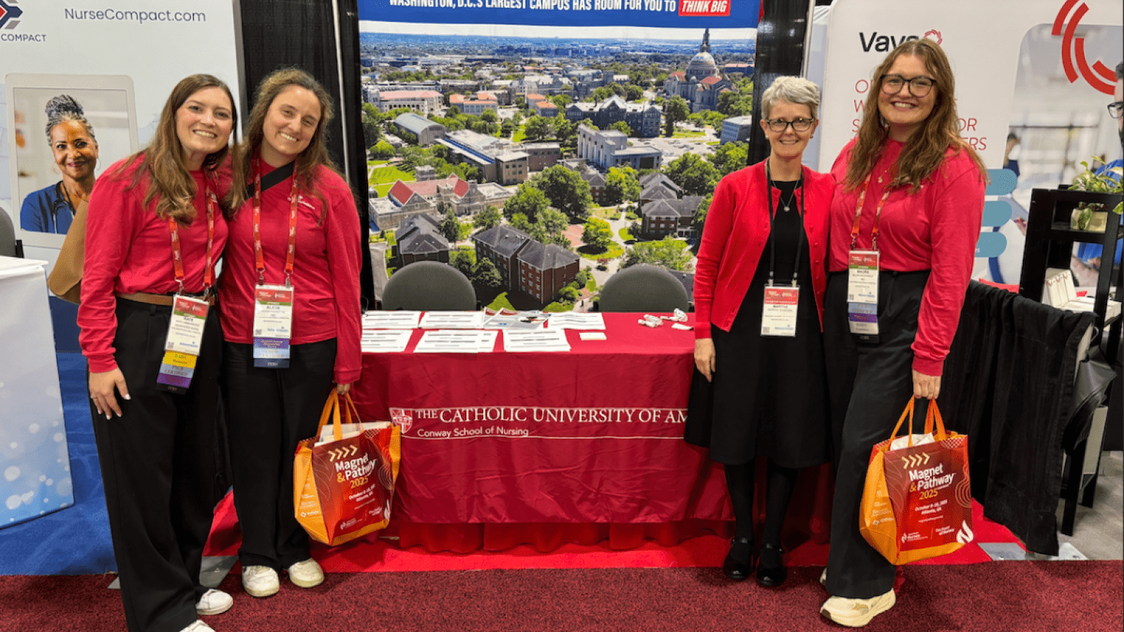 Photo of 3 Conway Nursing students and a professor in front of a table at a conference.