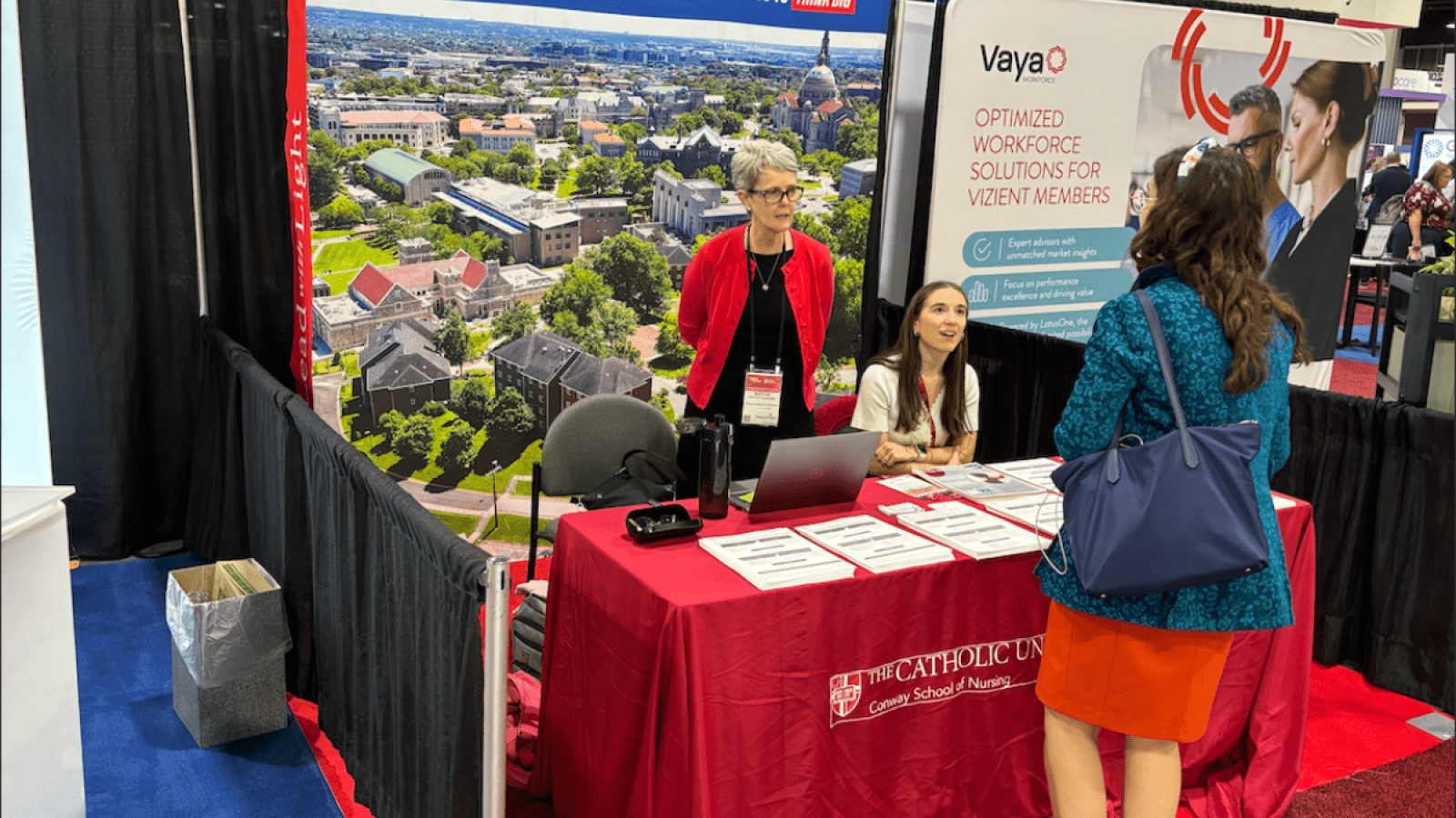 Conway Nursing professor and student speaking to a conference attendee.