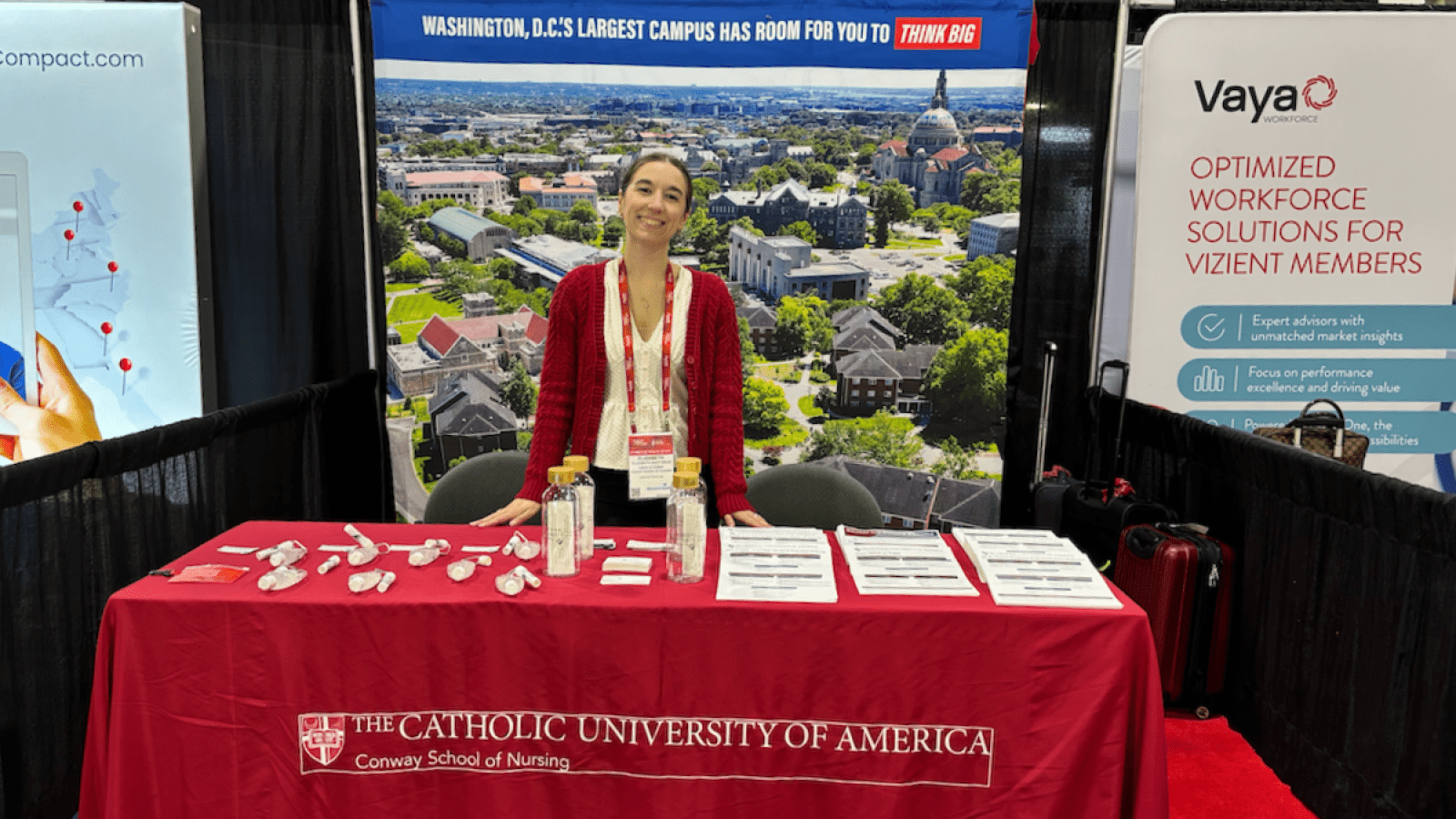 A Conway university representative standing behind the Catholic University table at the conference.