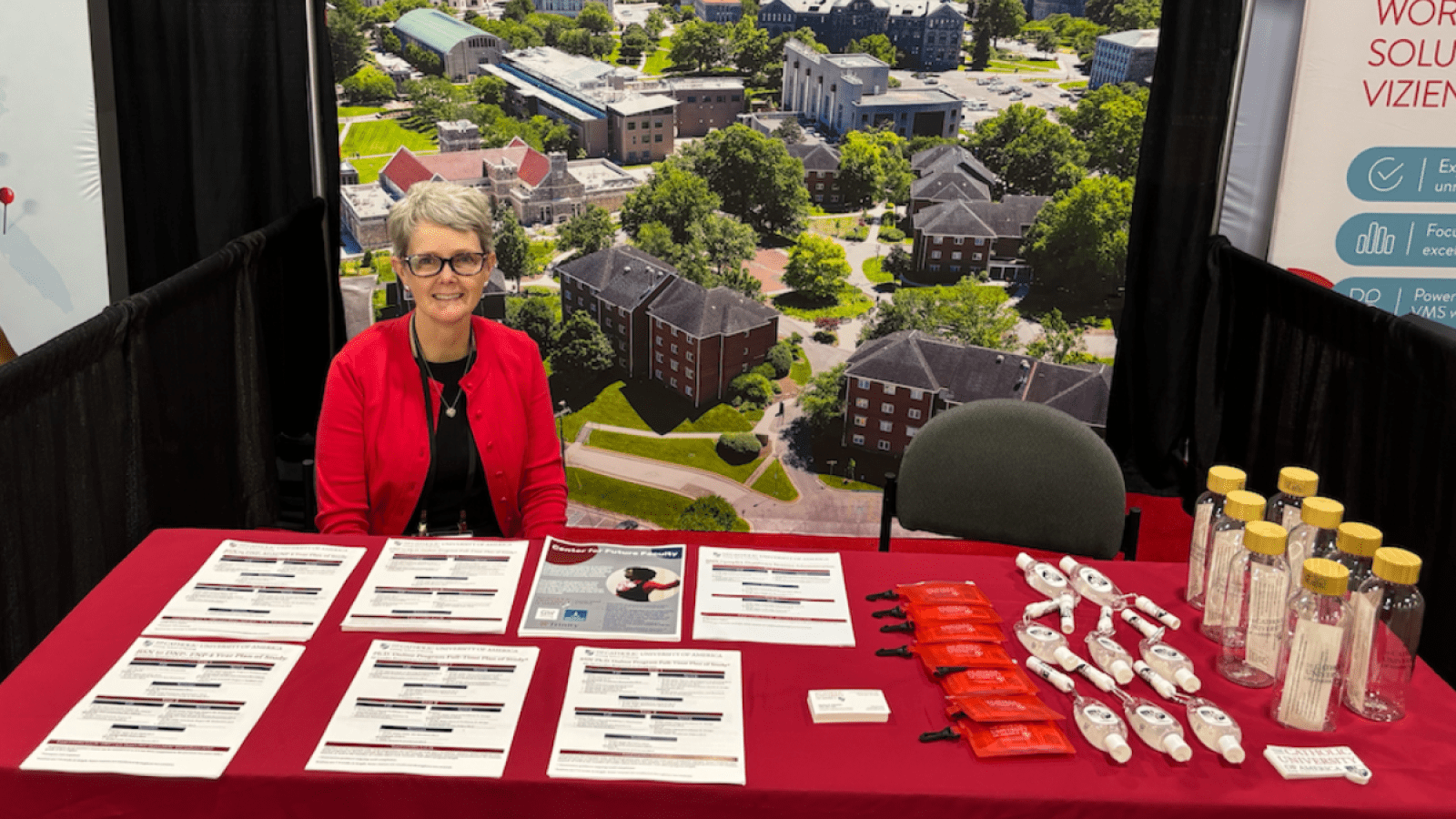 Conway School of Nursing representative behind the table at the conference with paper and pens.