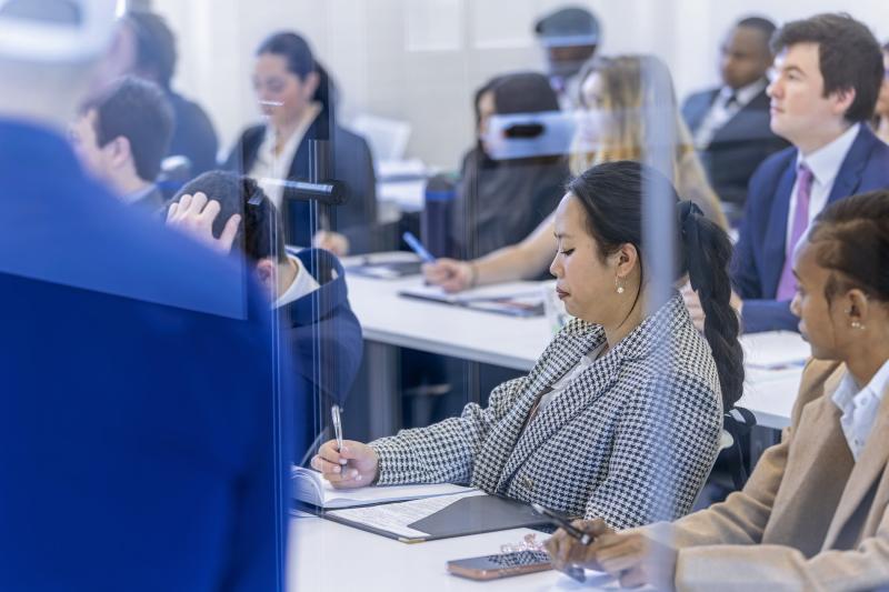 woman dressed professionally taking notes in a classroom