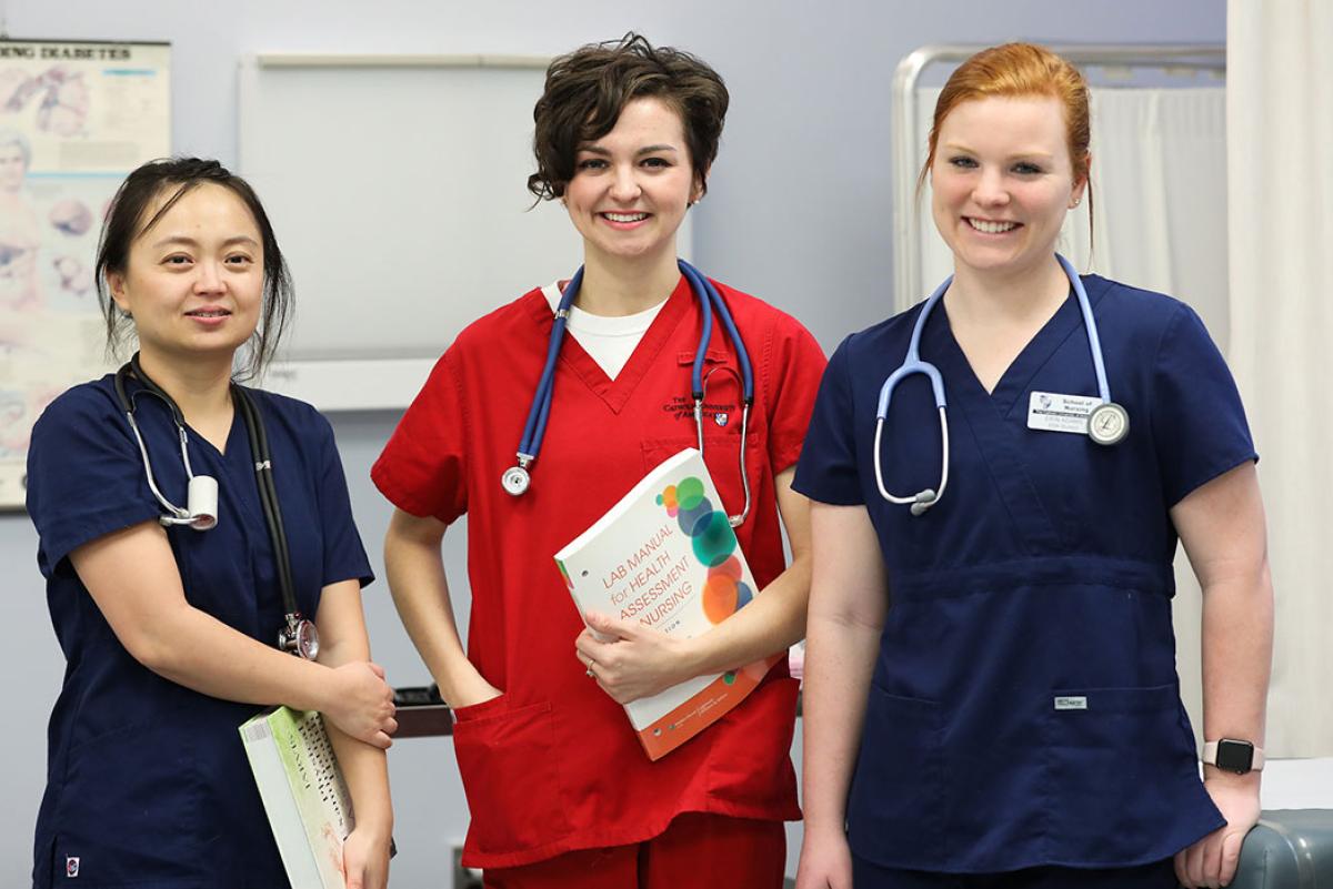 Nurses gathered in a patient room.
