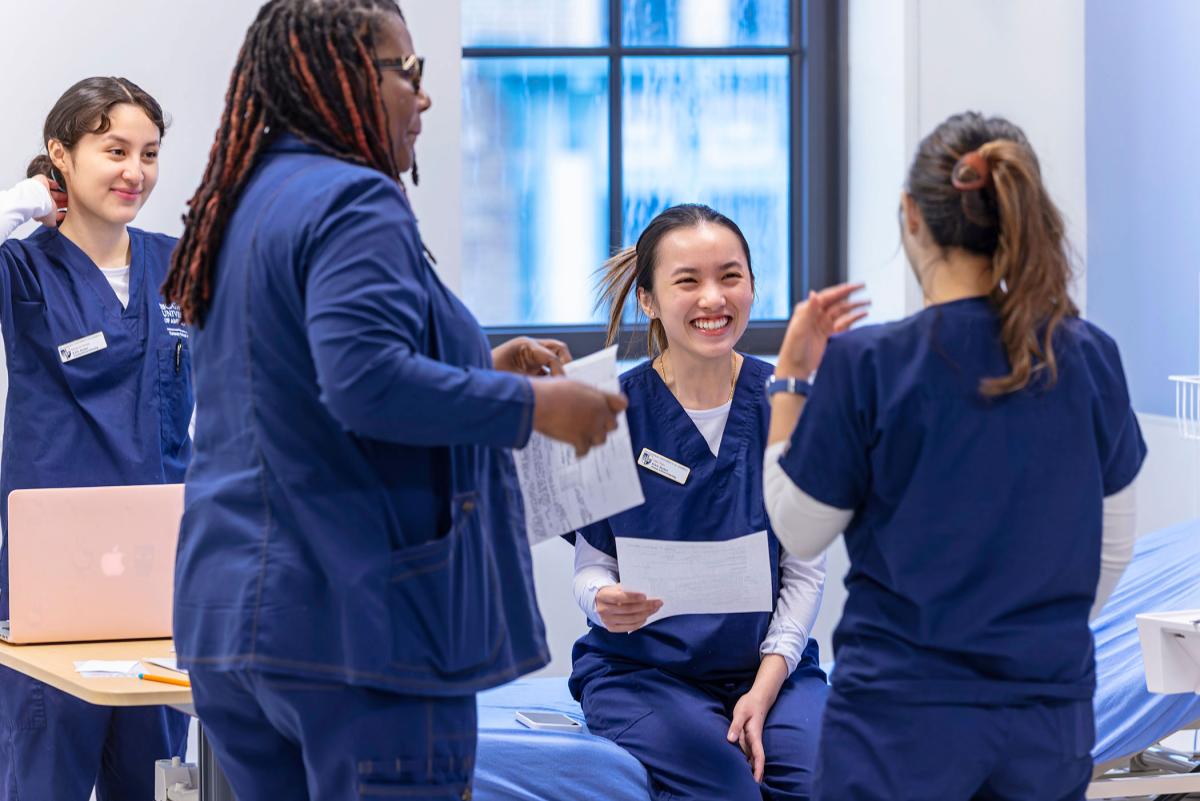 Nursing students reviewing procedures in exam room.
