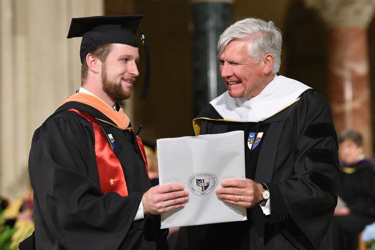 Bill Conway handing a diploma to a student at graduation
