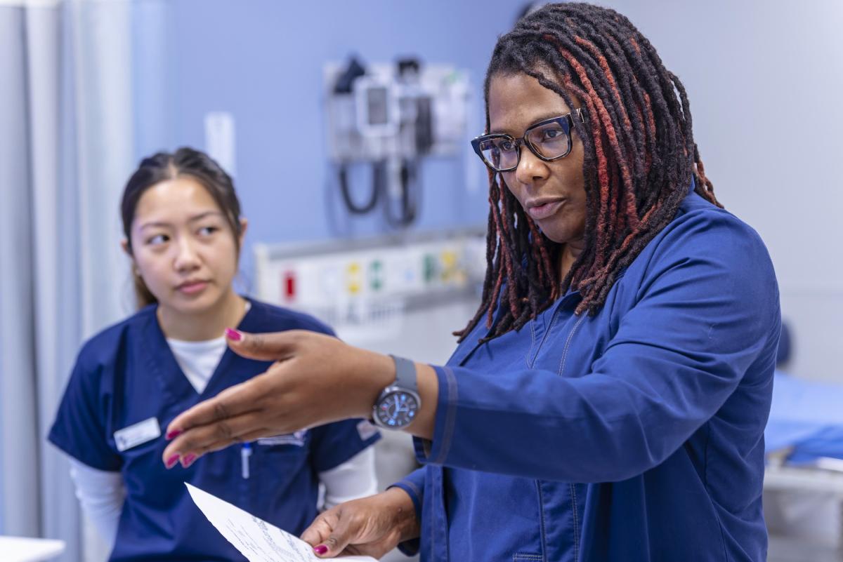 a nursing instructor instructing her students in a simulation room