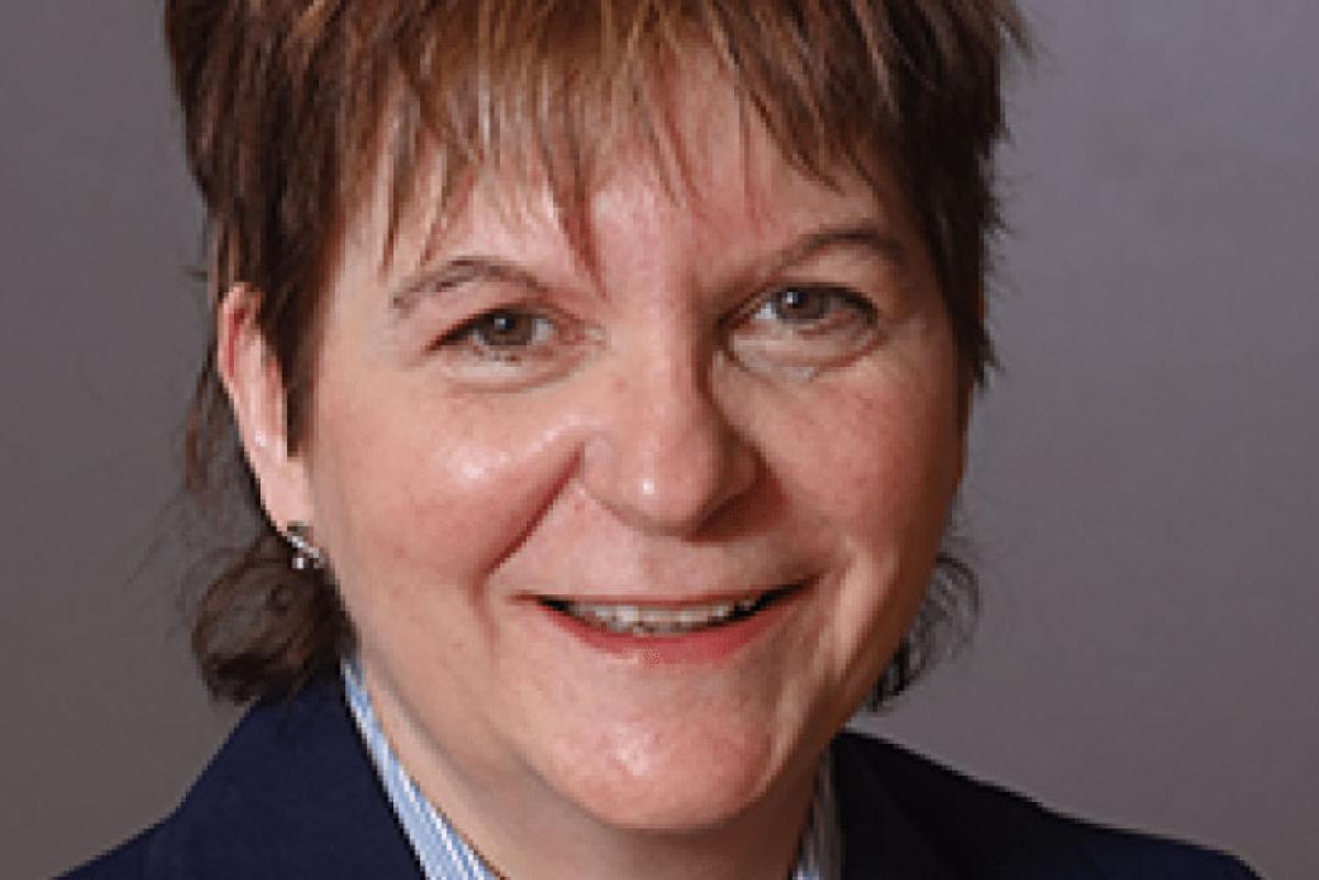 Photo of Sandra O'Brien. She has short brown hair and is wearing a navy blazer over a light blue shirt.