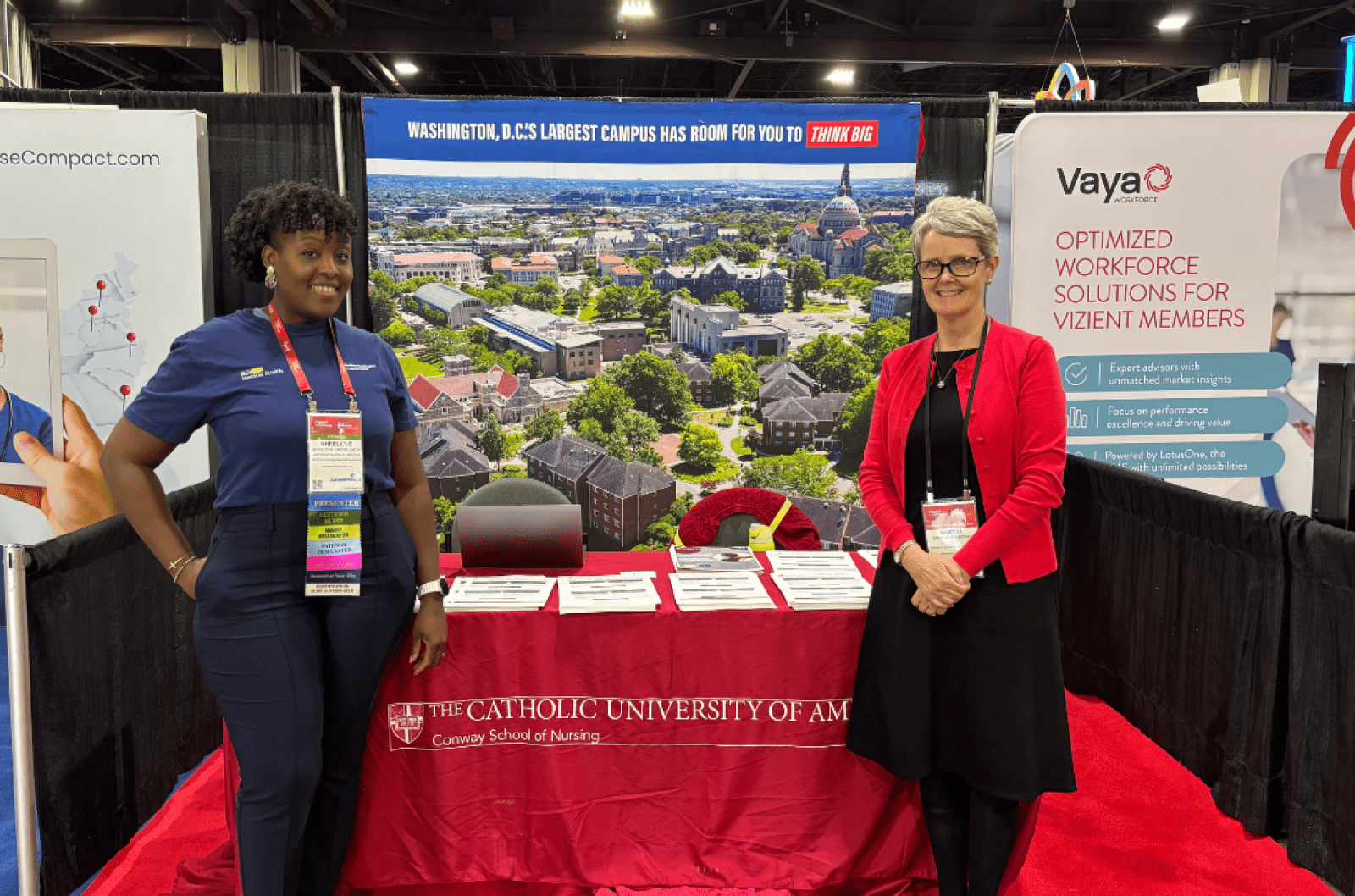 A Conway Nursing professor and student standing in front of a table at a conference.