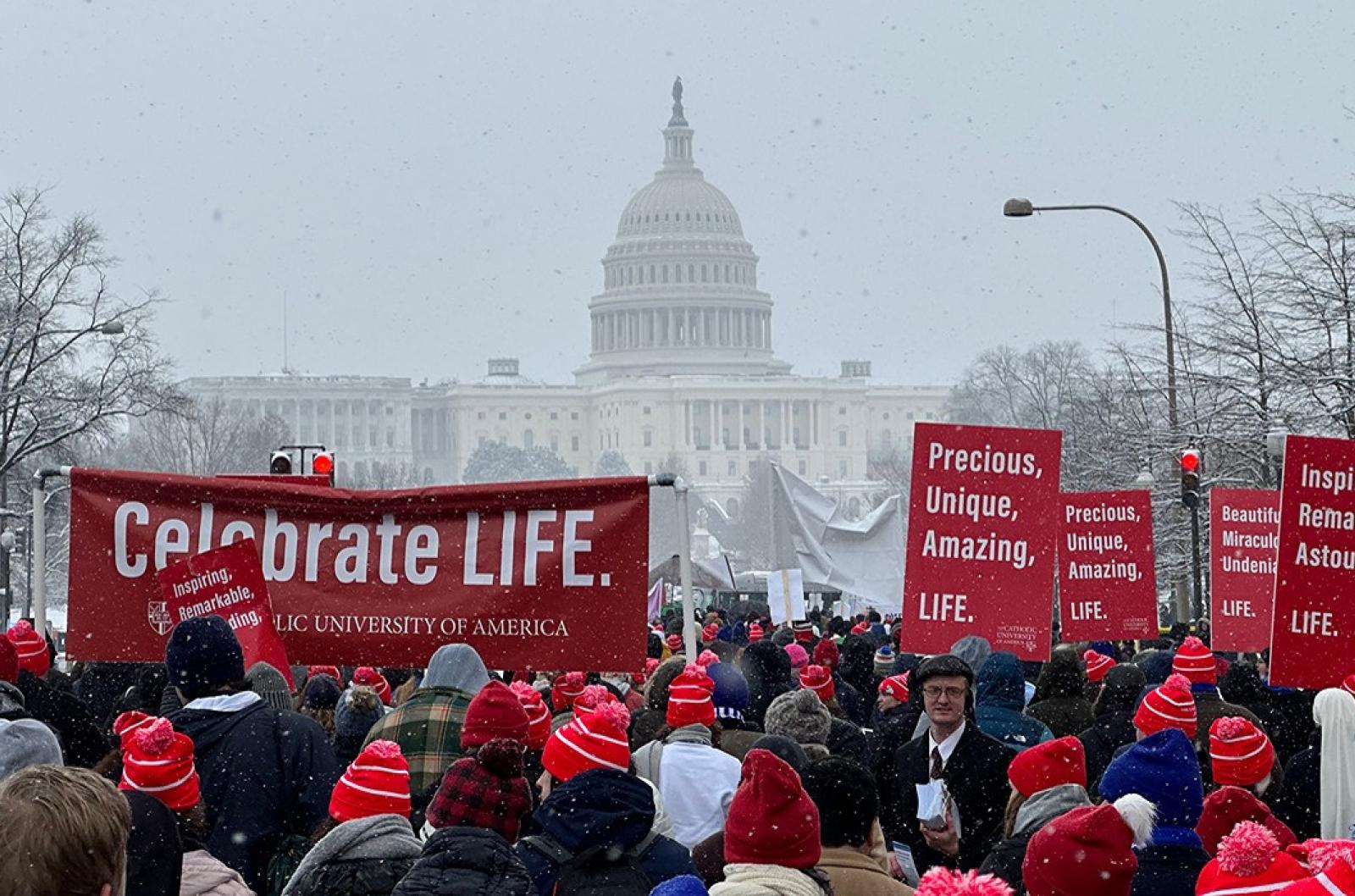Catholic University students marching towards the snowy Capitol building.