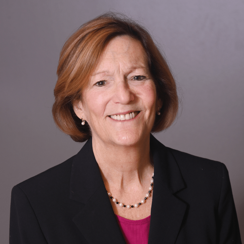 Photo of Mary Dixon. She has a brunette bob and is wearing a black blazer over a pink shirt.