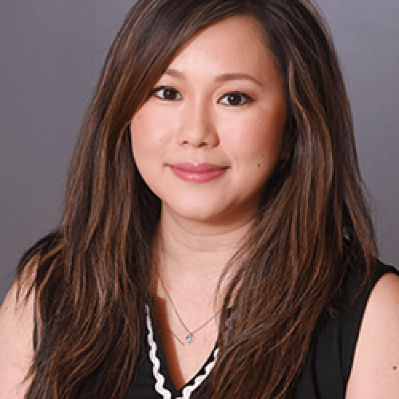 Photo of Reiko Asano. She has long brown hair. She is wearing a black shirt with white trim. 