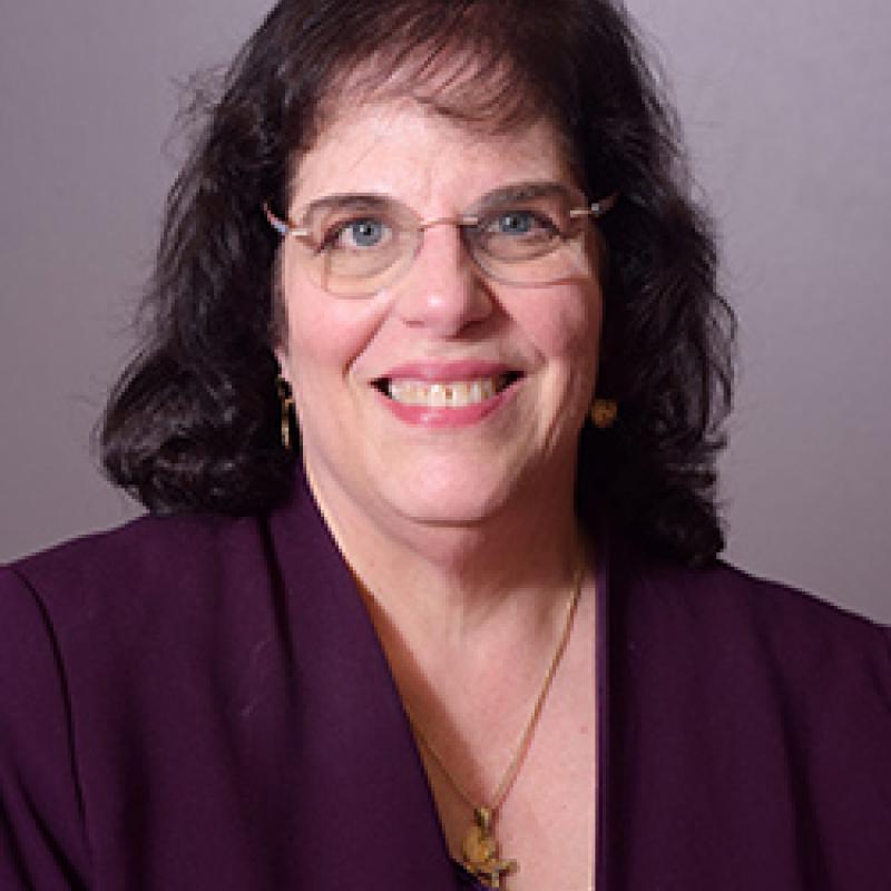 Photo of Marysanta Bigony. She has shoulder-length hair and glasses. She is wearing a purple blazer and shirt.