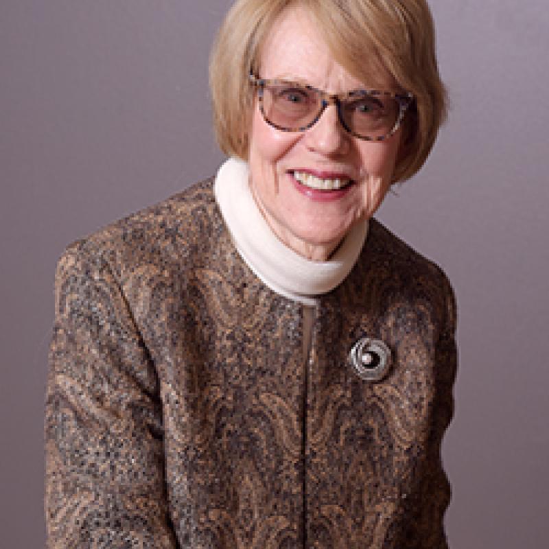 Photo of Eileen Caulfield. She has dark glasses and blonde hair with a paisley and white turtleneck.