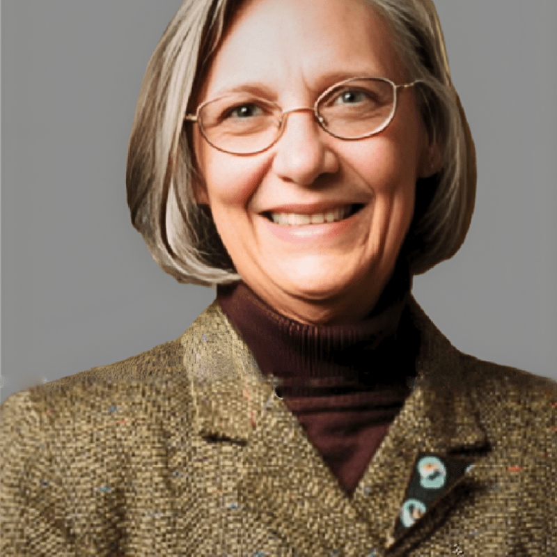 Photo of Mary A. Paterson. She has a grey bob and is wearing a tweed blazer over a brown turtleneck.