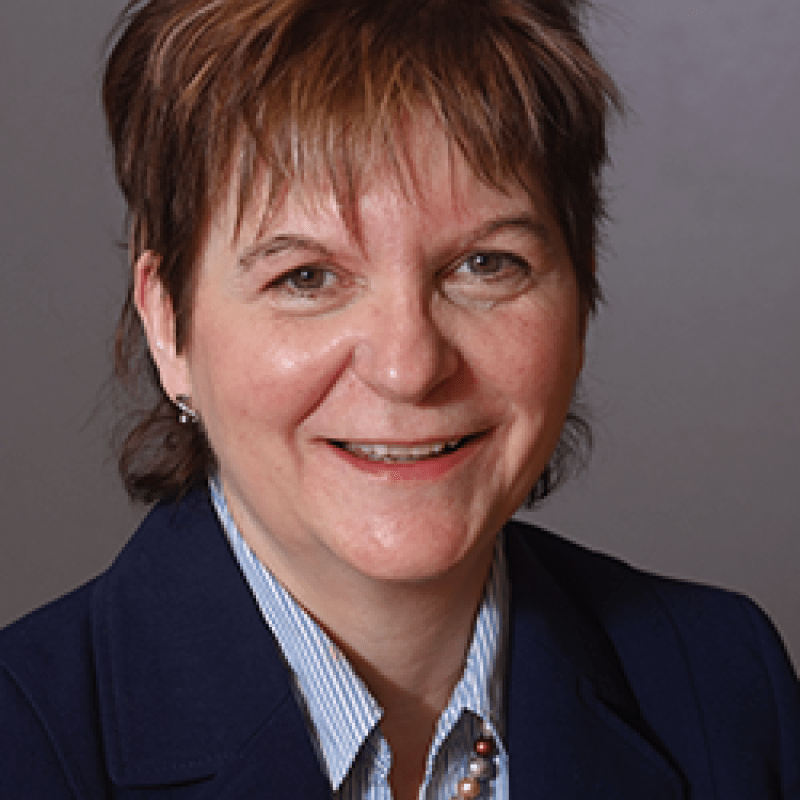 Photo of Sandra O'Brien. She has short brown hair and is wearing a navy blazer over a light blue shirt.