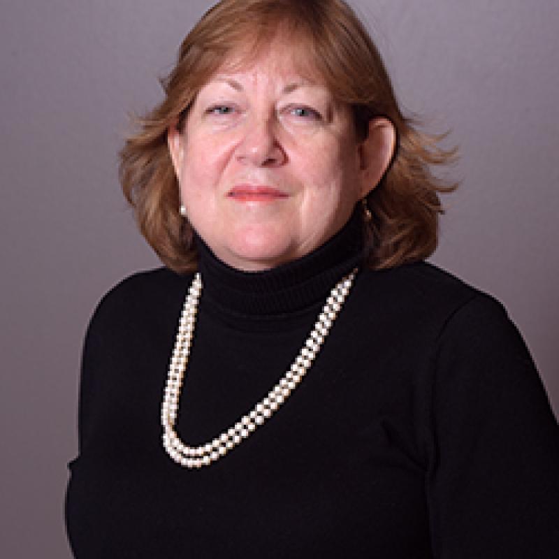 Photo of Patti Connor Ballard, wearing a black turtleneck with pearls.