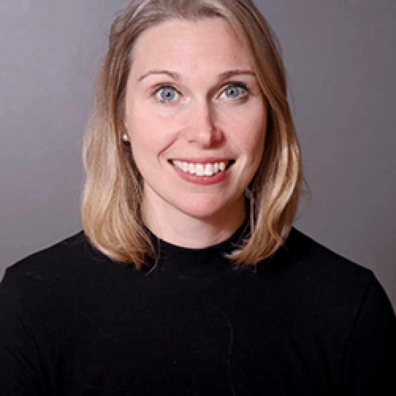 Photo of Maura Wenzel. She had shoulder-length blonde hair and is wearing a black turtleneck.