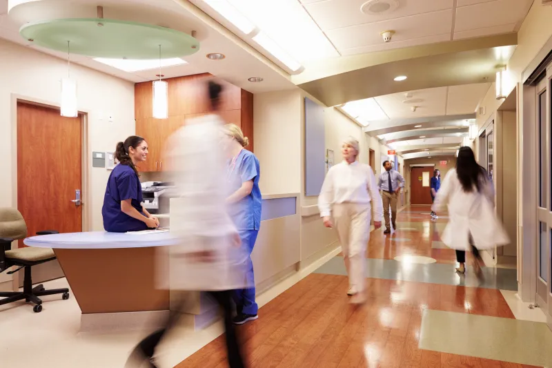 hospital hallway with nurses and doctors swiftly walking by