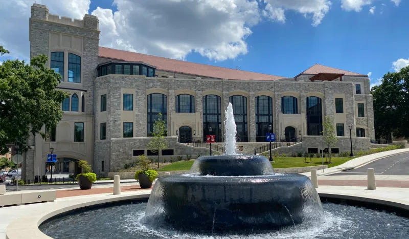 The new Conway School of Nursing building in the summer with the full green trees and a blue sky.