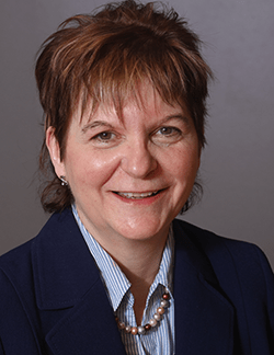 Photo of Sandra O'Brien. She has short brown hair and is wearing a navy blazer over a light blue shirt.