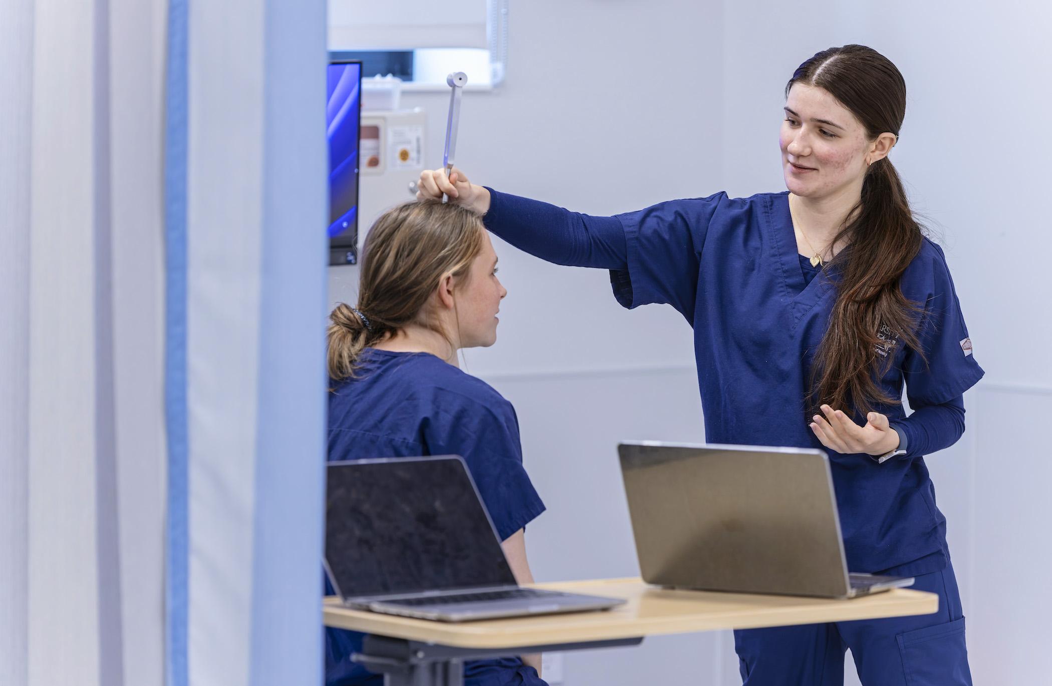 student performing a clinical simulation on another student