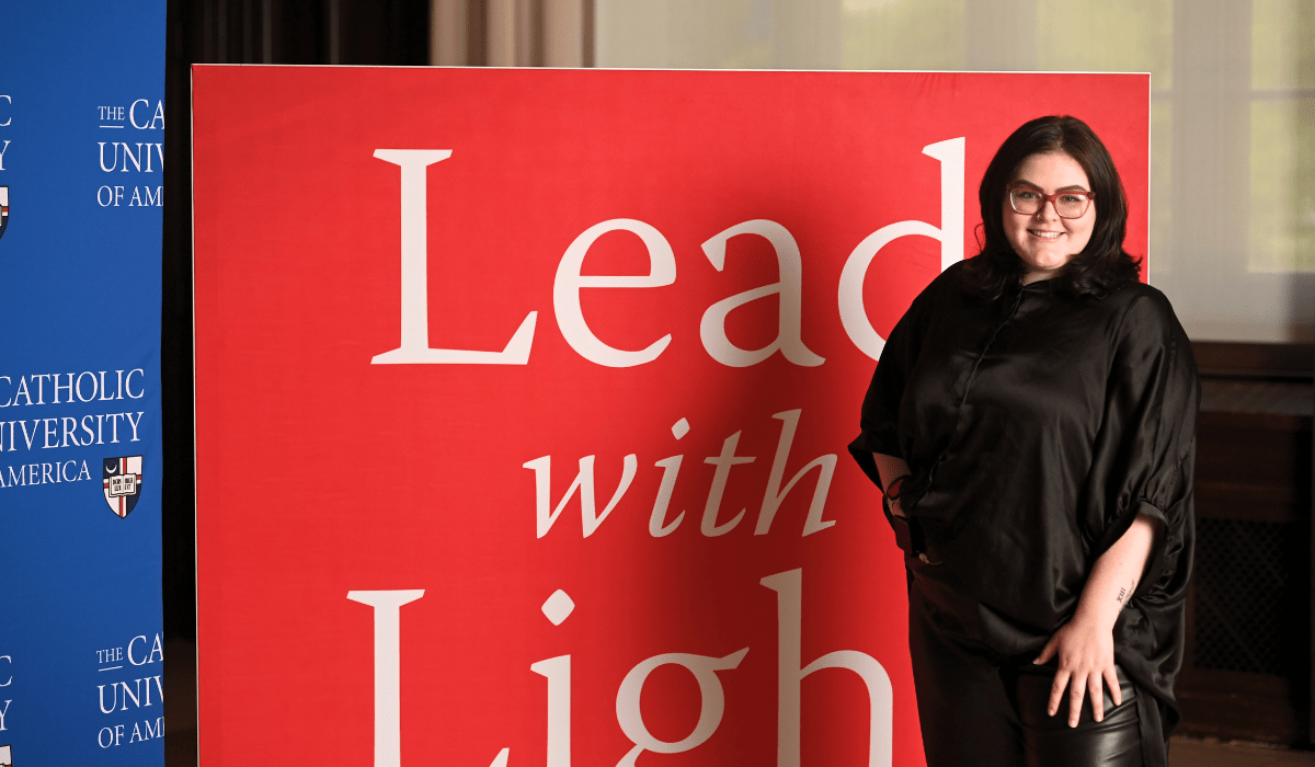 olivia by a sign that says "Lead with Light"